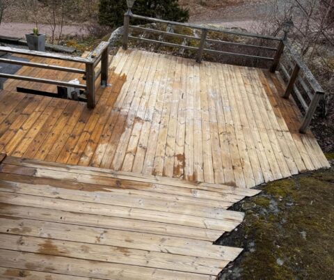 Rengjord träaltan med fasta sittbänkar, räcke och trappsteg ned mot berget.