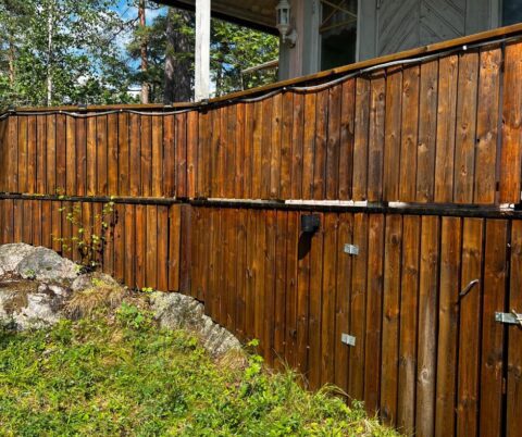 Rengjort, vått träräcke ovanför en bergkant med synlig träådring.
