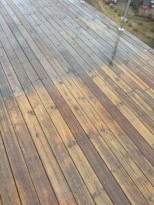 Träaltan med en tydlig gräns mellan grå trall och den nyligen rengjorda, våta ytan.